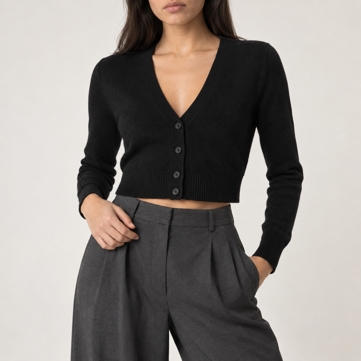 Model wearing the cropped V-neck cardigan in black with grey pleated trousers